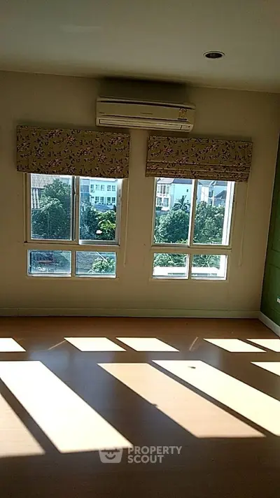 Bright room with large windows and air conditioning, offering a view of greenery outside.