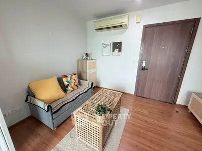 Cozy living room with modern decor and air conditioning, featuring a stylish sofa and wooden coffee table.