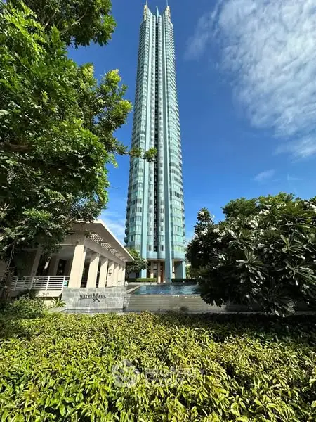Stunning skyscraper with lush greenery and clear blue sky, perfect urban living.