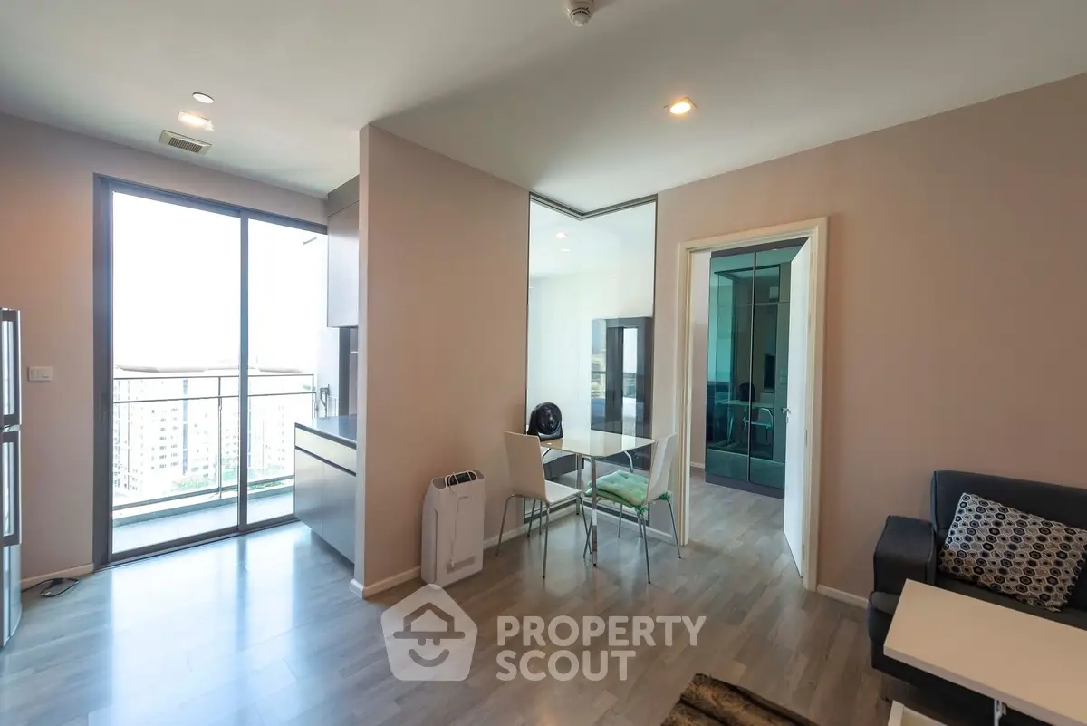 Modern apartment interior with open layout, featuring a cozy living area and dining space with large windows.