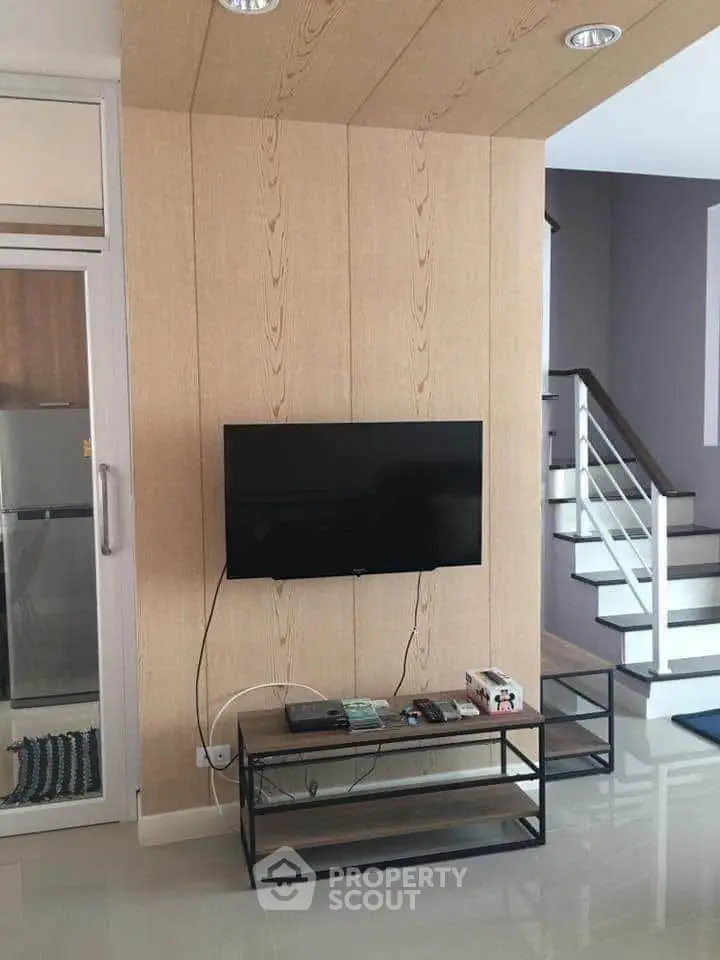 Modern living room with wall-mounted TV and sleek staircase