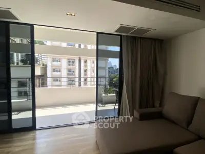 Spacious living room with large sliding doors opening to a sunny balcony with city views.