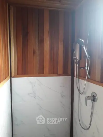 Compact wooden shower area with marble tiles and modern fixtures