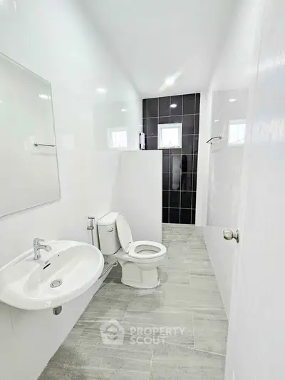 Modern minimalist bathroom with sleek fixtures and stylish black accent wall.