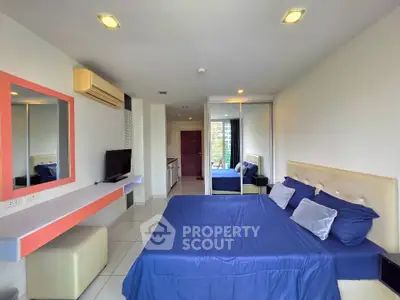 Modern bedroom with blue bedding, mirrored closet, and wall-mounted TV in stylish apartment.