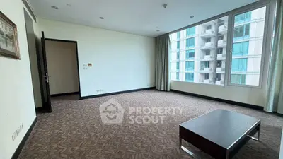 Spacious living room with large windows and modern decor in a high-rise apartment.