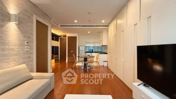 Modern living room with open kitchen, wooden flooring, and stylish decor in a contemporary apartment.
