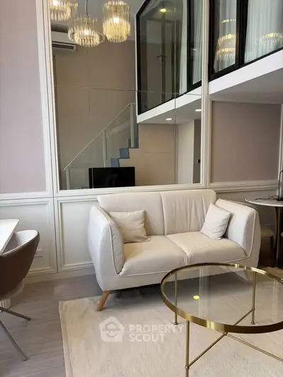 Modern living room with elegant decor, featuring a cozy sofa, glass coffee table, and stylish lighting.