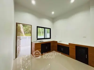 Modern kitchen with sleek design and ample natural light, featuring wooden cabinets and a spacious countertop.