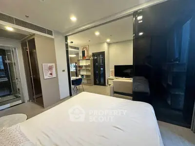 Modern bedroom with open layout leading to a stylish living area, featuring sleek furniture and contemporary decor.