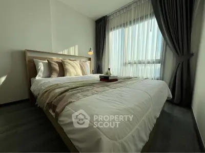 Cozy bedroom with large window and elegant curtains, perfect for relaxation.