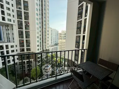 Charming balcony view in high-rise apartment with cityscape and lush greenery.