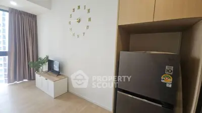Modern living room with stylish wall clock and sleek refrigerator in a cozy apartment.