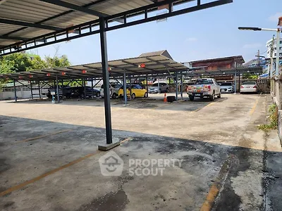 Spacious covered parking area with multiple vehicles and clear sky view.