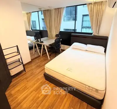 Modern bedroom with study area, featuring large windows and wooden flooring.