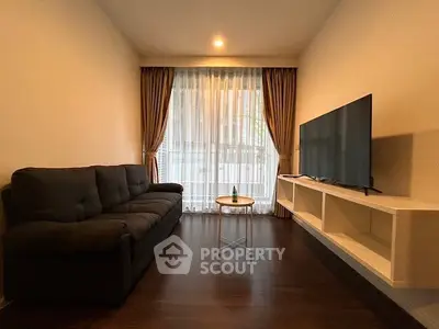 Cozy living room with dark sofa, large TV, and elegant curtains in modern apartment.