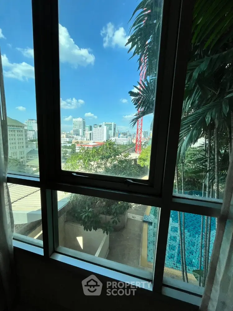 Stunning city view from high-rise window overlooking urban skyline and pool area.