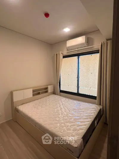 Cozy bedroom with natural light and modern air conditioning unit, perfect for restful nights.