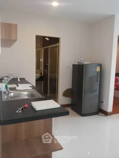 Modern kitchen with sleek design and stainless steel fridge in open layout apartment.