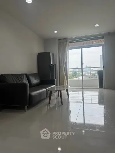 Modern living room with sleek black sofa and city view balcony, perfect for urban living.
