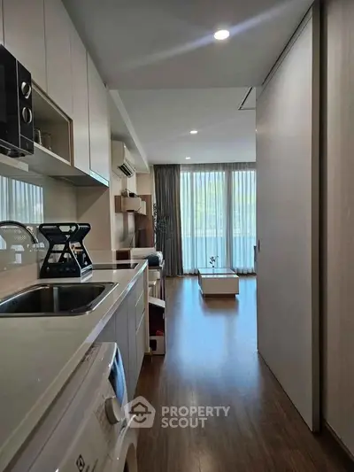 Modern apartment interior with sleek kitchen and spacious living area, featuring large windows and stylish decor.