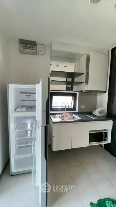 Modern kitchen with open fridge and sleek cabinetry in a contemporary apartment.