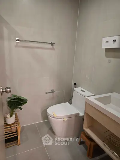 Modern bathroom with sleek fixtures and minimalist design, featuring a compact toilet and stylish sink.