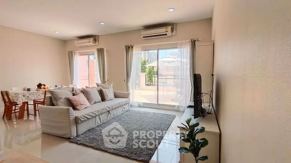 Spacious living room with modern decor and large windows opening to a balcony.