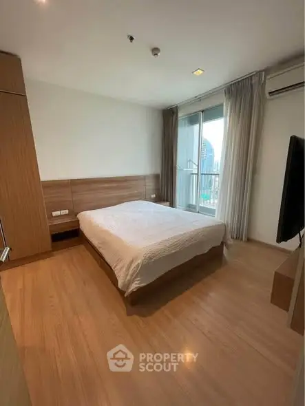 Spacious bedroom with modern design and city view balcony access.