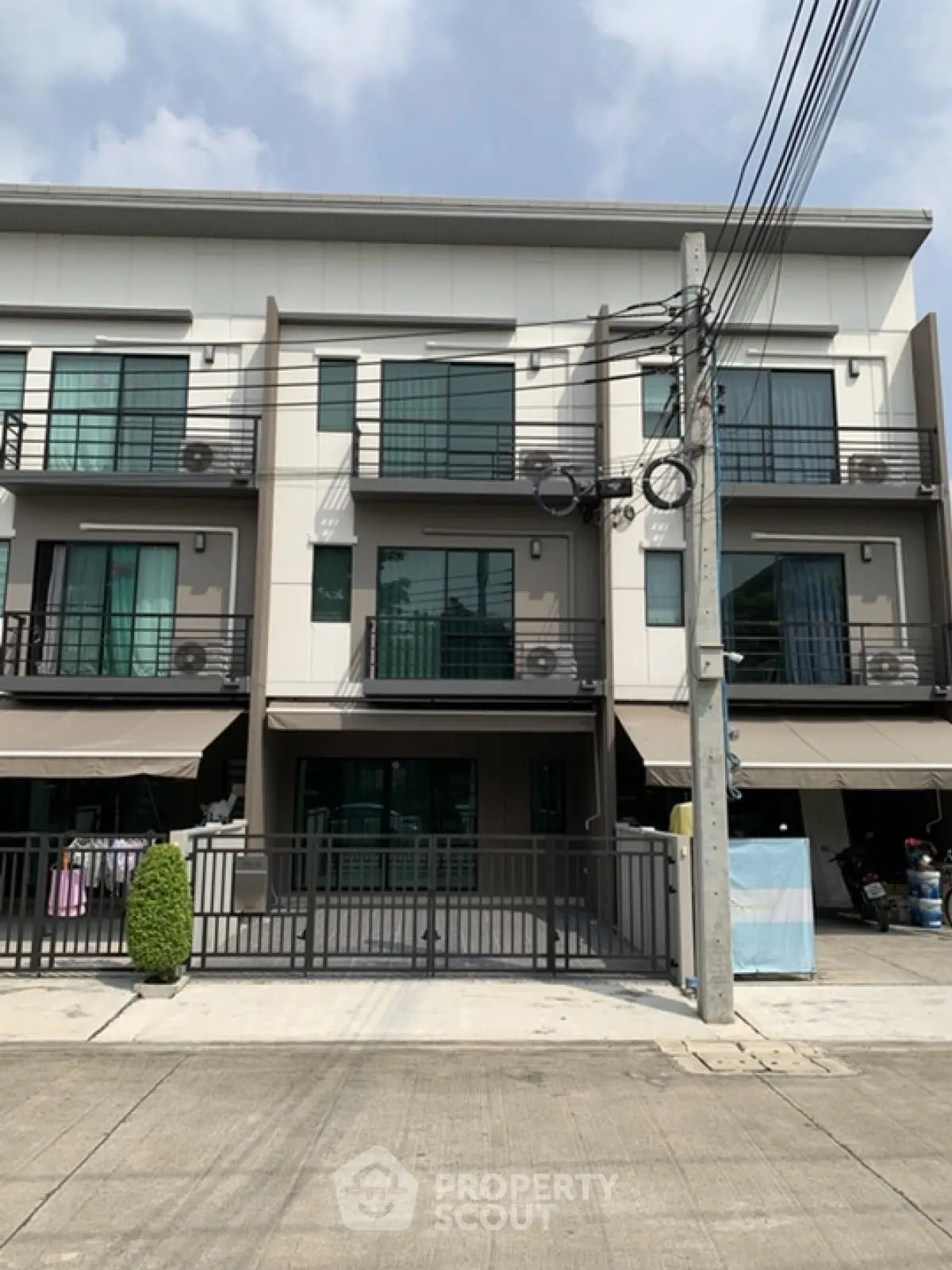 Modern three-story townhouse with balconies and gated entrance