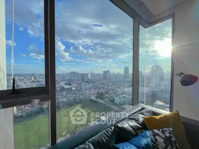 Stunning cityscape view from modern high-rise apartment with large windows and cozy seating area.