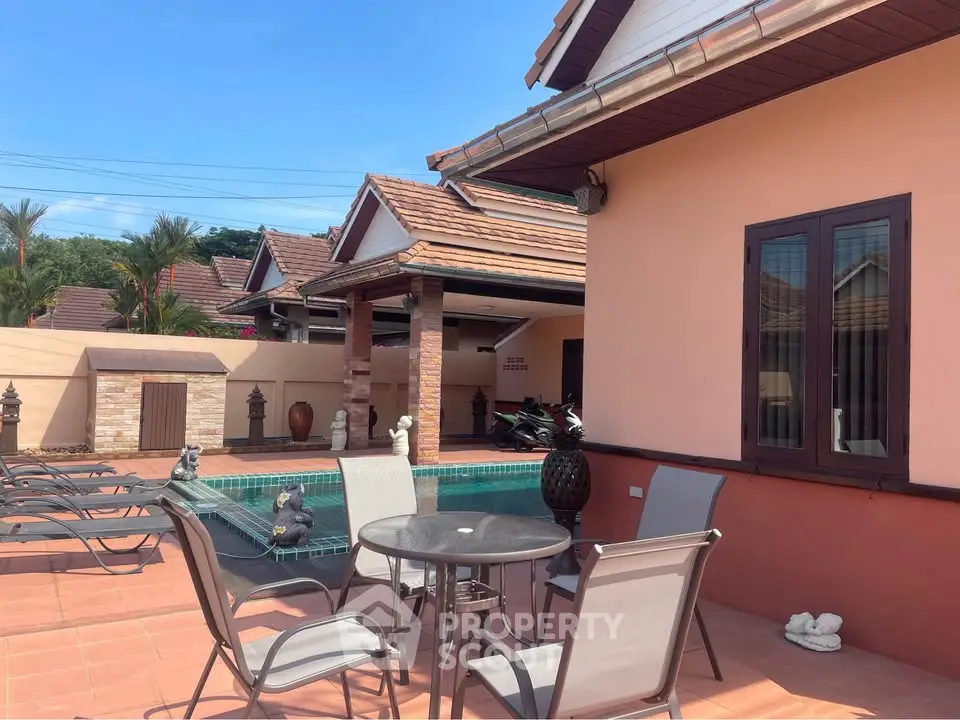 Charming villa with poolside patio and elegant outdoor seating in tropical setting.