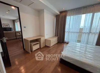Spacious bedroom with wooden flooring and modern furniture in a high-rise apartment.