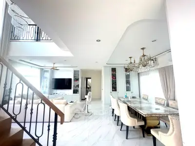 Luxurious open-plan living and dining area with elegant chandeliers and modern decor.