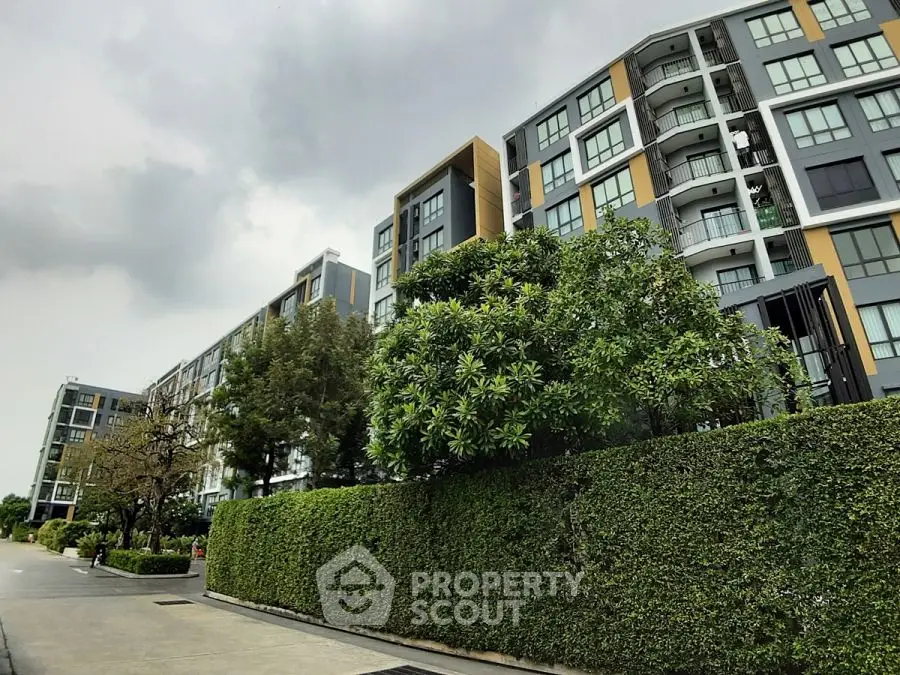 Modern apartment building with lush greenery and overcast sky, showcasing urban living.