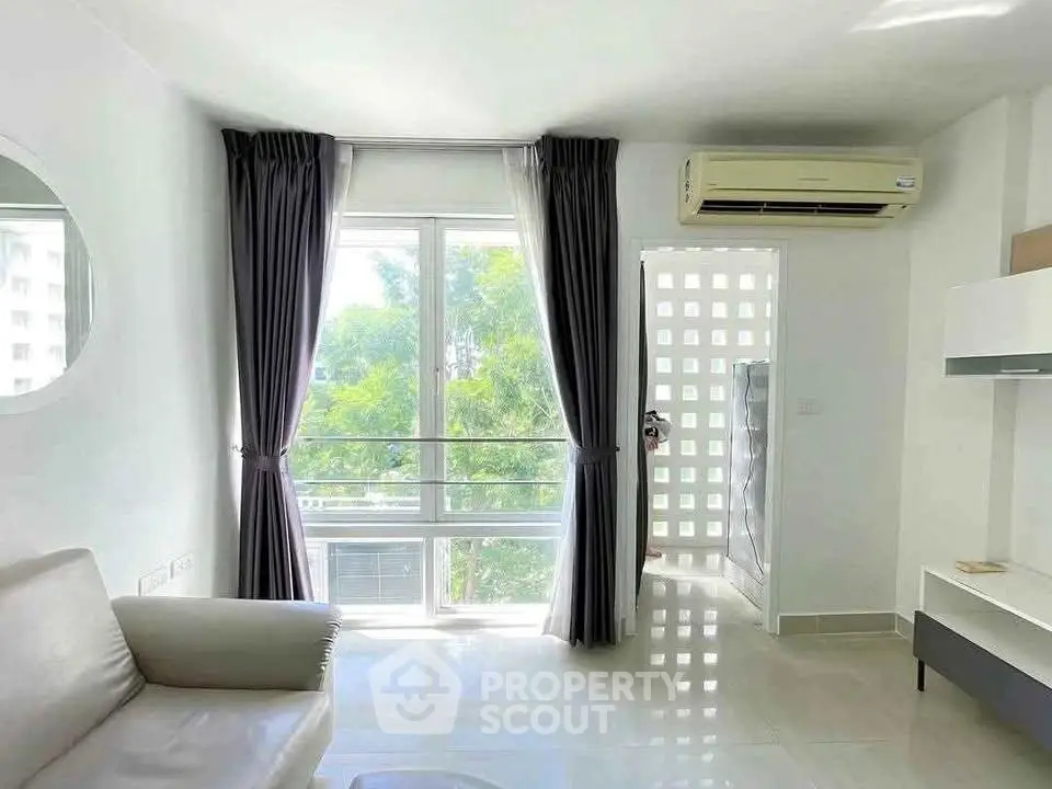 Bright living room with large window, modern air conditioning, and sleek white decor.