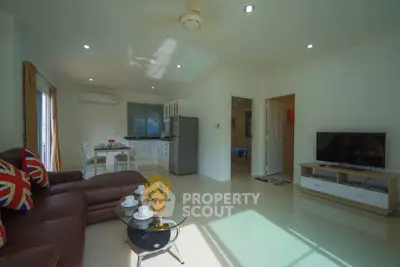 Spacious living room with modern kitchen in open layout, featuring stylish decor and ample natural light.