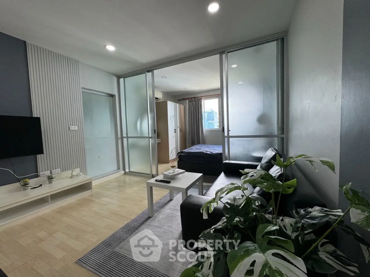 Modern living room with glass partition and cozy bedroom view