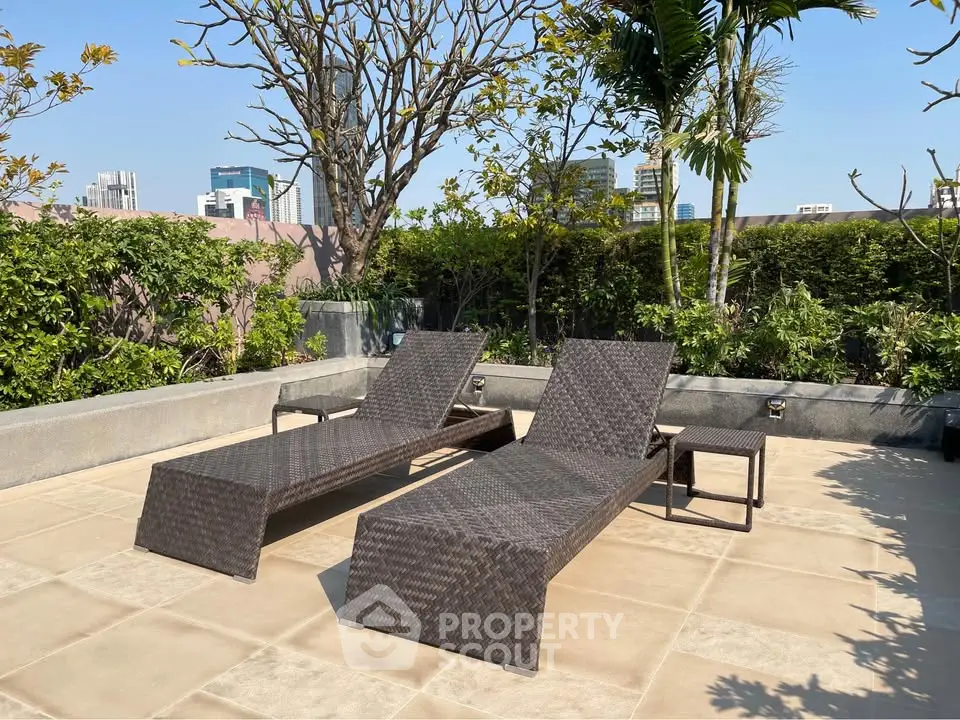 Luxurious rooftop terrace with stylish sun loungers and lush greenery, offering a serene urban escape.