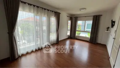 Spacious empty room with large windows and wooden flooring