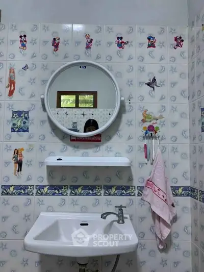 Charming bathroom with playful cartoon-themed tiles and round mirror, perfect for a family-friendly home.
