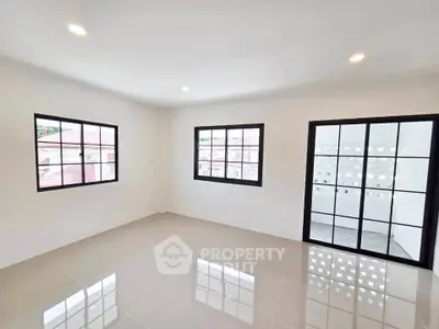 Spacious and bright living room with large windows and modern tile flooring.