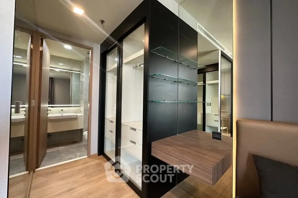 Modern interior with sleek storage and bathroom view, featuring glass shelves and wood accents.