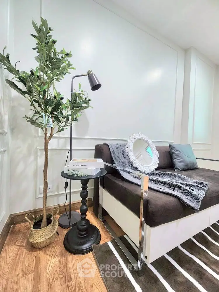 Stylish living room corner with modern sofa, elegant lamp, and decorative plant for a cozy ambiance.