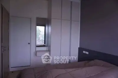 Cozy bedroom with modern wardrobe and window view, perfect for relaxation and comfort.