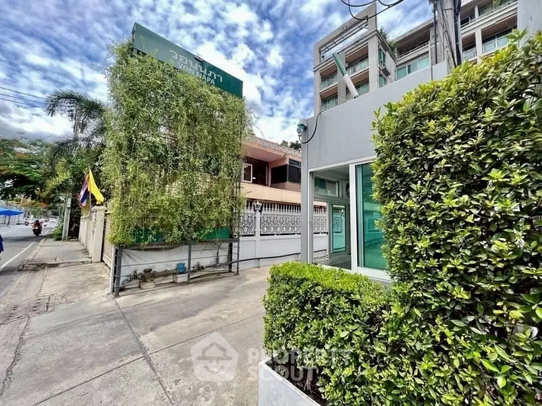 Modern urban building exterior with lush greenery and clear sky