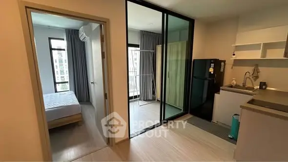 Modern apartment interior with bedroom, kitchen, and balcony view.