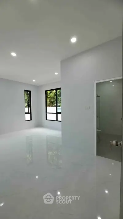 Spacious modern living room with large windows and glossy white flooring, perfect for natural light lovers.