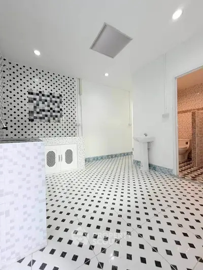 Spacious bathroom with modern black and white tile design and sleek fixtures.