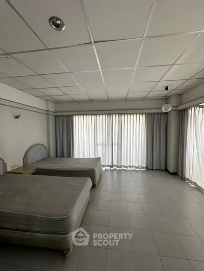 Spacious bedroom with twin beds and large windows for natural light.